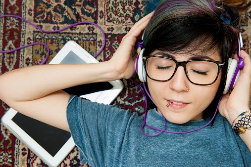 Pretty young woman lying with headphones and tablet